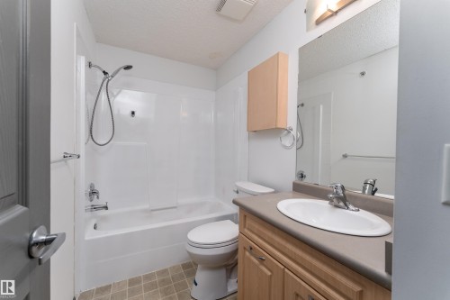 Full bath with vanity, a textured ceiling, washtub / shower combination, and light flooring - 101 6220 134 Avenue, Edmonton, AB - Indoor Photo Showing Bathroom