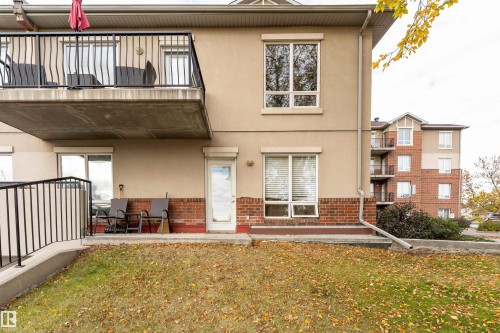 Back of house with a balcony, stucco siding, brick siding, and a yard - 101 6220 134 Avenue, Edmonton, AB - Outdoor With Balcony