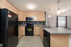 Kitchen featuring black appliances, a peninsula, light countertops, hanging light fixtures, and a textured ceiling - 