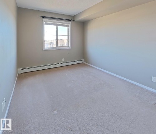 Carpeted empty room with a baseboard radiator and baseboards - 404 5370 Chappelle Road, Edmonton, AB - Indoor Photo Showing Other Room
