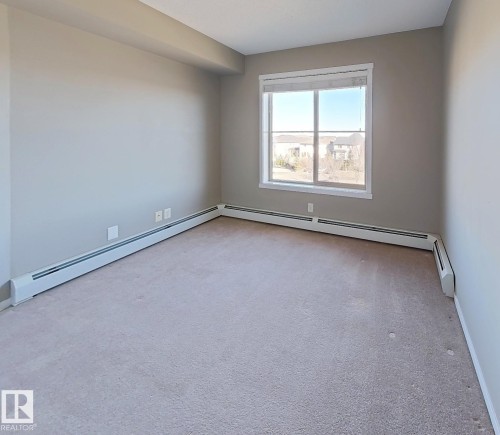 Spare room featuring light carpet and baseboard heating - 404 5370 Chappelle Road, Edmonton, AB - Indoor Photo Showing Other Room