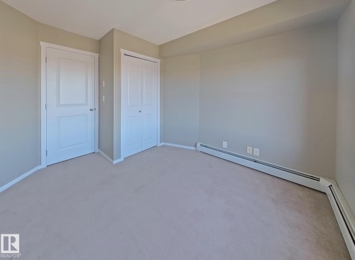 Unfurnished bedroom featuring carpet, a baseboard heating unit, and a closet - 404 5370 Chappelle Road, Edmonton, AB - Indoor Photo Showing Other Room