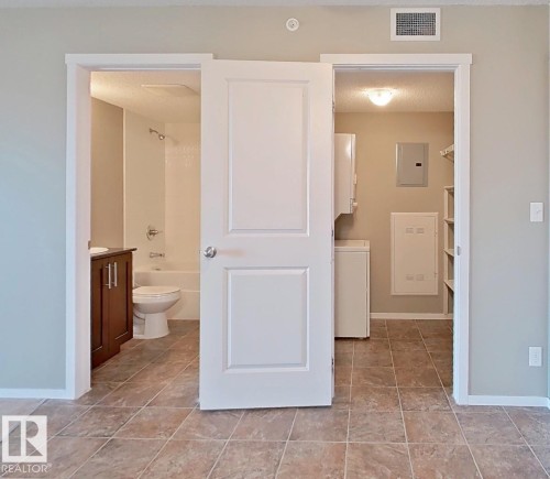 Bathroom with vanity, electric panel, shower / washtub combination, washer / clothes dryer, and light tile patterned floors - 404 5370 Chappelle Road, Edmonton, AB - Indoor Photo Showing Bathroom