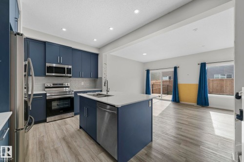 Kitchen featuring a kitchen island with sink, appliances with stainless steel finishes, blue cabinets, decorative backsplash, and recessed lighting - 1813 Collip View View, Edmonton, AB - Indoor Photo Showing Kitchen With Stainless Steel Kitchen With Double Sink With Upgraded Kitchen