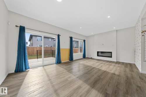 Unfurnished living room with a glass covered fireplace, light wood finished floors, and recessed lighting - 1813 Collip View View, Edmonton, AB - Indoor Photo Showing Other Room With Fireplace