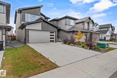 Modern home featuring stone siding, concrete driveway, an attached garage, and a residential view - 1813 Collip View View, Edmonton, AB - Outdoor