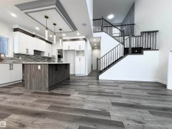 Kitchen with white cabinets, a towering ceiling, decorative light fixtures, modern cabinets, and decorative backsplash - 