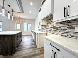 Kitchen featuring white cabinets, a textured ceiling, light stone counters, decorative light fixtures, and decorative backsplash - 