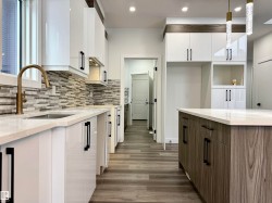 Kitchen featuring white cabinetry, light stone countertops, dark wood finished floors, hanging light fixtures, and modern cabinets - 