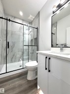 Full bathroom featuring vanity, a textured ceiling, a marble finish shower, and dark wood-style flooring - 