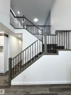 Stairs with a towering ceiling, wood finished floors, and recessed lighting - 