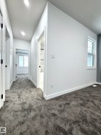 Hall featuring a textured ceiling and dark colored carpet - 