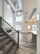 Stairs featuring a chandelier, a textured ceiling, wood finished floors, and a towering ceiling - 