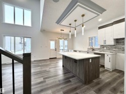 Kitchen with white cabinets, a textured ceiling, dark wood-style flooring, tasteful backsplash, and a kitchen island - 