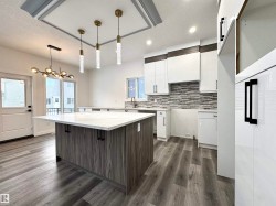 Kitchen featuring white cabinetry, a center island, pendant lighting, a textured ceiling, and a kitchen bar - 