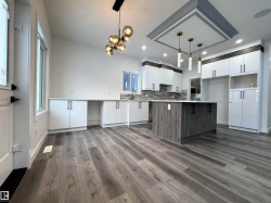 Kitchen with white cabinets, pendant lighting, tasteful backsplash, and modern cabinets - 