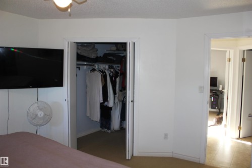 Carpeted bedroom featuring baseboards and a textured ceiling - 5221 54A Street, Elk Point, AB - Indoor
