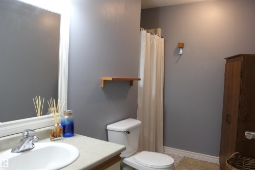 Bathroom featuring vanity, light tile patterned flooring, and a shower with shower curtain - 5221 54A Street, Elk Point, AB - Indoor Photo Showing Bathroom