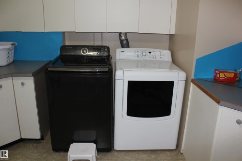 Laundry area featuring cabinet space, independent washer and dryer, and light tile patterned floors - 5221 54A Street, Elk Point, AB - Indoor Photo Showing Laundry Room