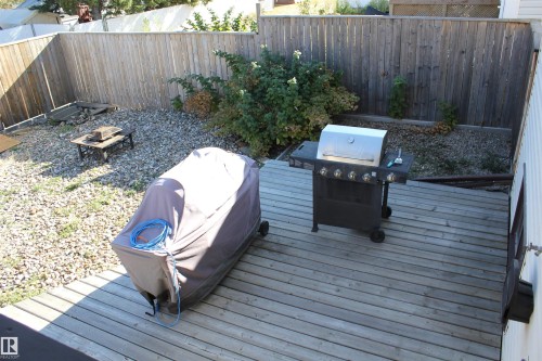 Deck with area for grilling, a fenced backyard, and an outdoor fire pit - 5221 54A Street, Elk Point, AB - Outdoor With Deck Patio Veranda
