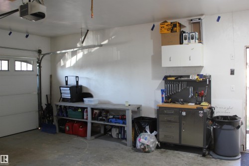 Garage with a garage door opener and a workshop area - 5221 54A Street, Elk Point, AB - Indoor Photo Showing Garage