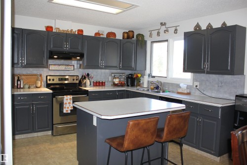 Kitchen with tasteful backsplash, stainless steel electric range oven, light countertops, a kitchen island, and a textured ceiling - 5221 54A Street, Elk Point, AB - Indoor Photo Showing Kitchen With Double Sink