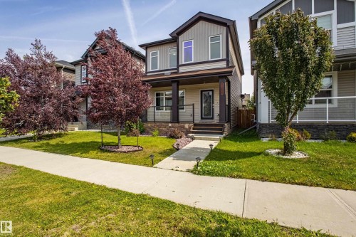 View of front facade featuring a porch, a front lawn, board and batten siding, and stone siding - 2407 Casey Link, Edmonton, AB - Outdoor With Facade