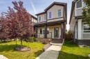 View of front of home featuring a porch, board and batten siding, a front yard, and stone siding - 2407 Casey Link, Edmonton, AB  - Outdoor With Deck Patio Veranda With Facade 