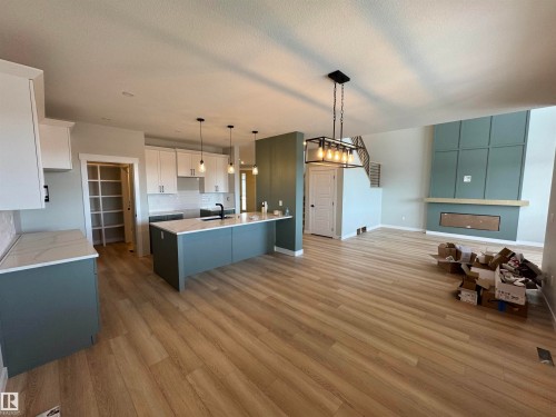Two tone kitchen featuring open floor plan, pendant lighting, dual tone cabinetry, a breakfast bar area, and light wood-style flooring - 28 Harley Way, Spruce Grove, AB - Indoor Photo Showing Kitchen