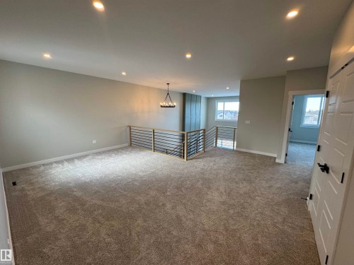 Spare room with light carpet and a chandelier - 28 Harley Way, Spruce Grove, AB - Indoor Photo Showing Other Room
