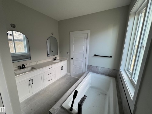 Full bathroom with double vanity, light tile patterned floors, and a garden tub - 28 Harley Way, Spruce Grove, AB - Indoor