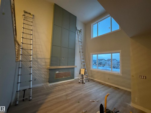 Unfurnished living room featuring a high ceiling, wood finished floors, and plenty of natural light - 28 Harley Way, Spruce Grove, AB - Indoor Photo Showing Other Room With Fireplace