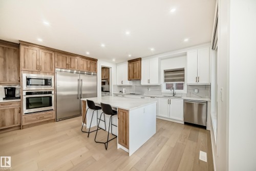 Kitchen with built in appliances, a breakfast bar area, backsplash, a kitchen island, and light wood-style floors - 42 Elwyck Gate, Spruce Grove, AB - Indoor Photo Showing Kitchen With Stainless Steel Kitchen With Upgraded Kitchen