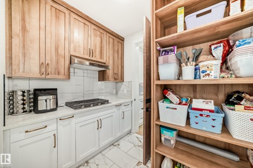 Kitchen featuring decorative backsplash, light marble finish flooring, under cabinet range hood, stainless steel gas stovetop, and light stone countertops - 42 Elwyck Gate, Spruce Grove, AB - Indoor