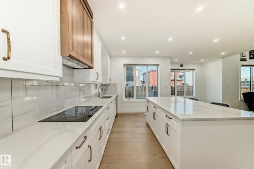 Kitchen featuring light stone countertops, a center island, tasteful backsplash, light wood-style flooring, and recessed lighting - 42 Elwyck Gate, Spruce Grove, AB - Indoor Photo Showing Kitchen With Upgraded Kitchen