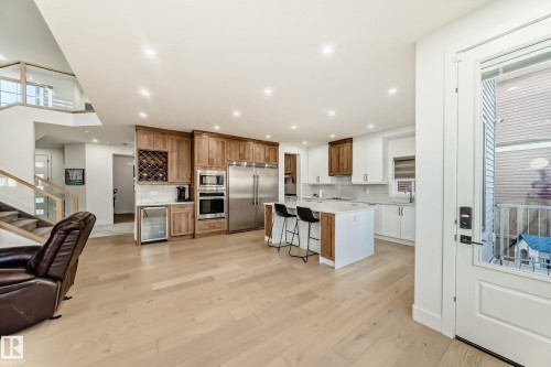 Kitchen with a kitchen breakfast bar, an island with sink, beverage cooler, light wood-type flooring, and built in appliances - 42 Elwyck Gate, Spruce Grove, AB - Indoor Photo Showing Kitchen With Stainless Steel Kitchen