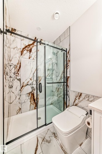 Full bathroom featuring tile walls, a marble finish shower, marble look tile flooring, vanity, and a textured ceiling - 42 Elwyck Gate, Spruce Grove, AB - Indoor