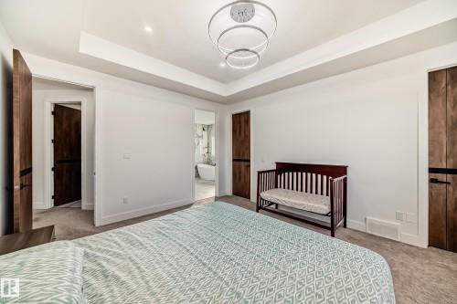 Carpeted bedroom with a raised ceiling, a nursery area, and ensuite bath - 42 Elwyck Gate, Spruce Grove, AB - Indoor Photo Showing Bedroom