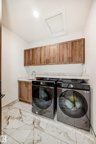 Washroom with light marble finish floors, washer and dryer, cabinet space, and attic access - 42 Elwyck Gate, Spruce Grove, AB - Indoor Photo Showing Laundry Room