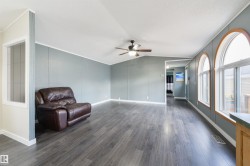 Sitting room with dark wood-type flooring, lofted ceiling, a ceiling fan, and crown molding - 