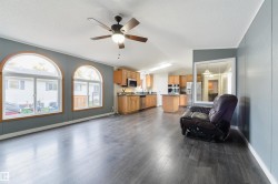 Living area featuring vaulted ceiling, dark wood-style flooring, a ceiling fan, and a textured ceiling - 