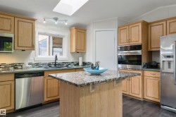 Kitchen with stainless steel appliances, a kitchen island, backsplash, a skylight, and a breakfast bar - 