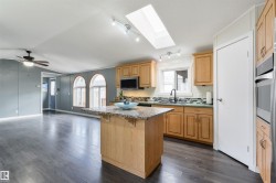 Kitchen featuring dark wood-style floors, decorative backsplash, a breakfast bar area, a center island, and open floor plan - 