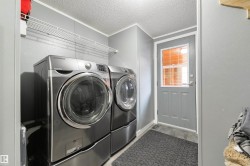 Laundry room with a textured ceiling, independent washer and dryer, light wood finished floors, and ornamental molding - 
