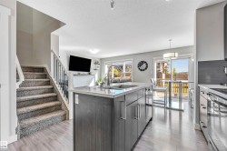 Kitchen featuring an island with sink, a textured ceiling, decorative light fixtures, appliances with stainless steel finishes, and modern cabinets - 