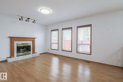 Family room featuring a high end fireplace, rail lighting, and light wood-type flooring - 4631 43 Avenue, Edmonton, AB - Indoor Photo Showing Living Room With Fireplace