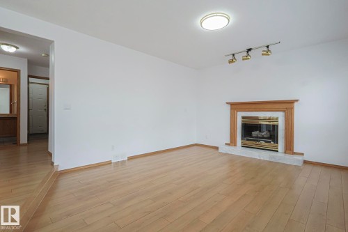 Family room featuring light wood-style floors, a glass covered fireplace, and track lighting - 4631 43 Avenue, Edmonton, AB - Indoor Photo Showing Living Room With Fireplace
