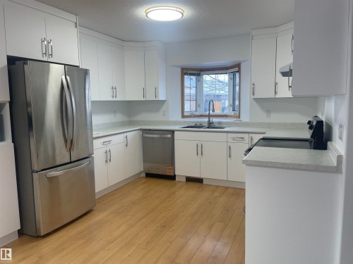 Kitchen featuring stainless steel appliances, new white cabinets, light countertops, and light wood-type flooring - 4631 43 Avenue, Edmonton, AB - Indoor Photo Showing Kitchen