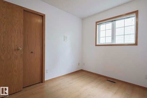 Main floor bedroom with light wood-style flooring, a closet, and a textured ceiling - 4631 43 Avenue, Edmonton, AB - Indoor Photo Showing Other Room