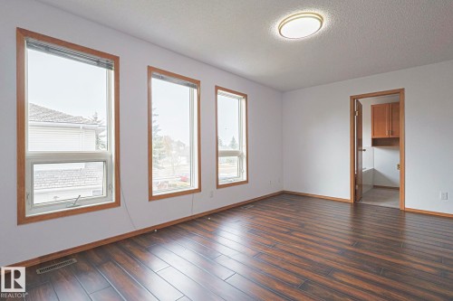 Empty room with a textured ceiling and dark wood-style flooring - 4631 43 Avenue, Edmonton, AB - Indoor Photo Showing Other Room